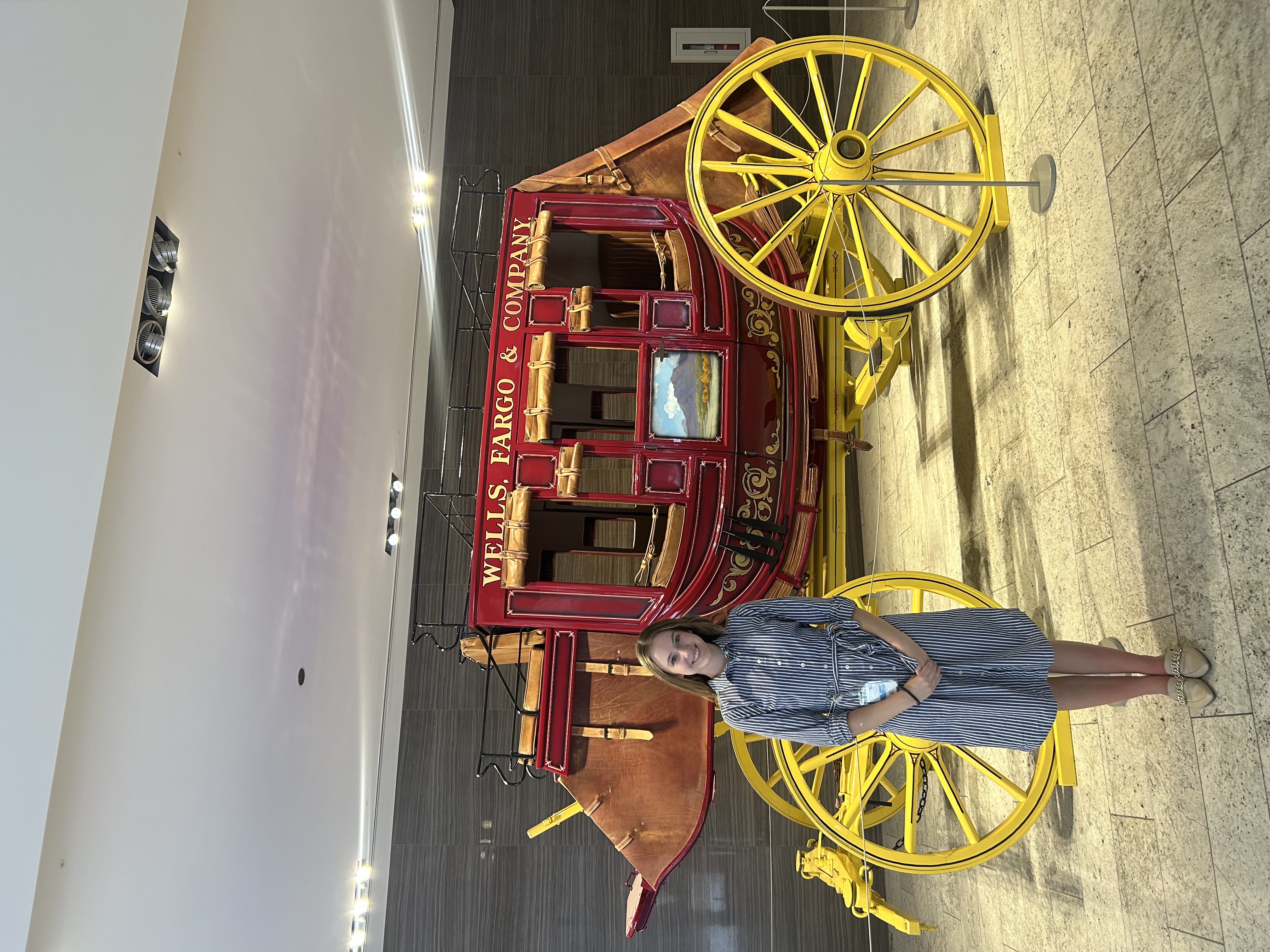 This is a photo of Ava in front of the Wells Fargo logo wagon located in their Chandler office